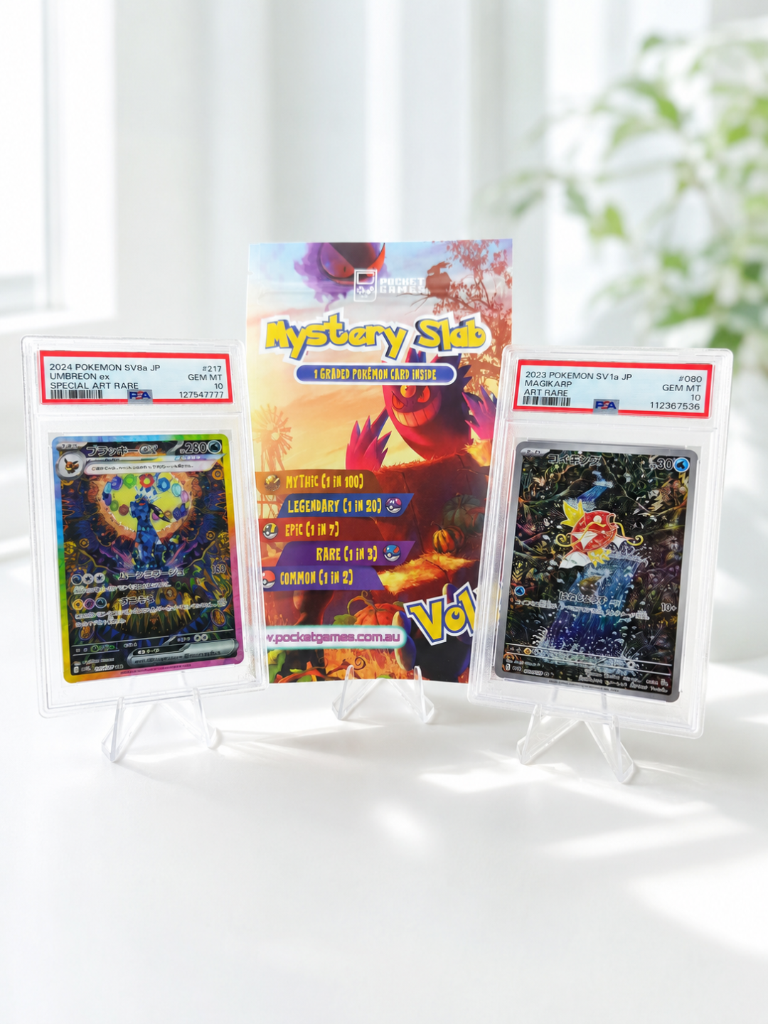 Three trading cards in protective sleeves on a white surface with a light background