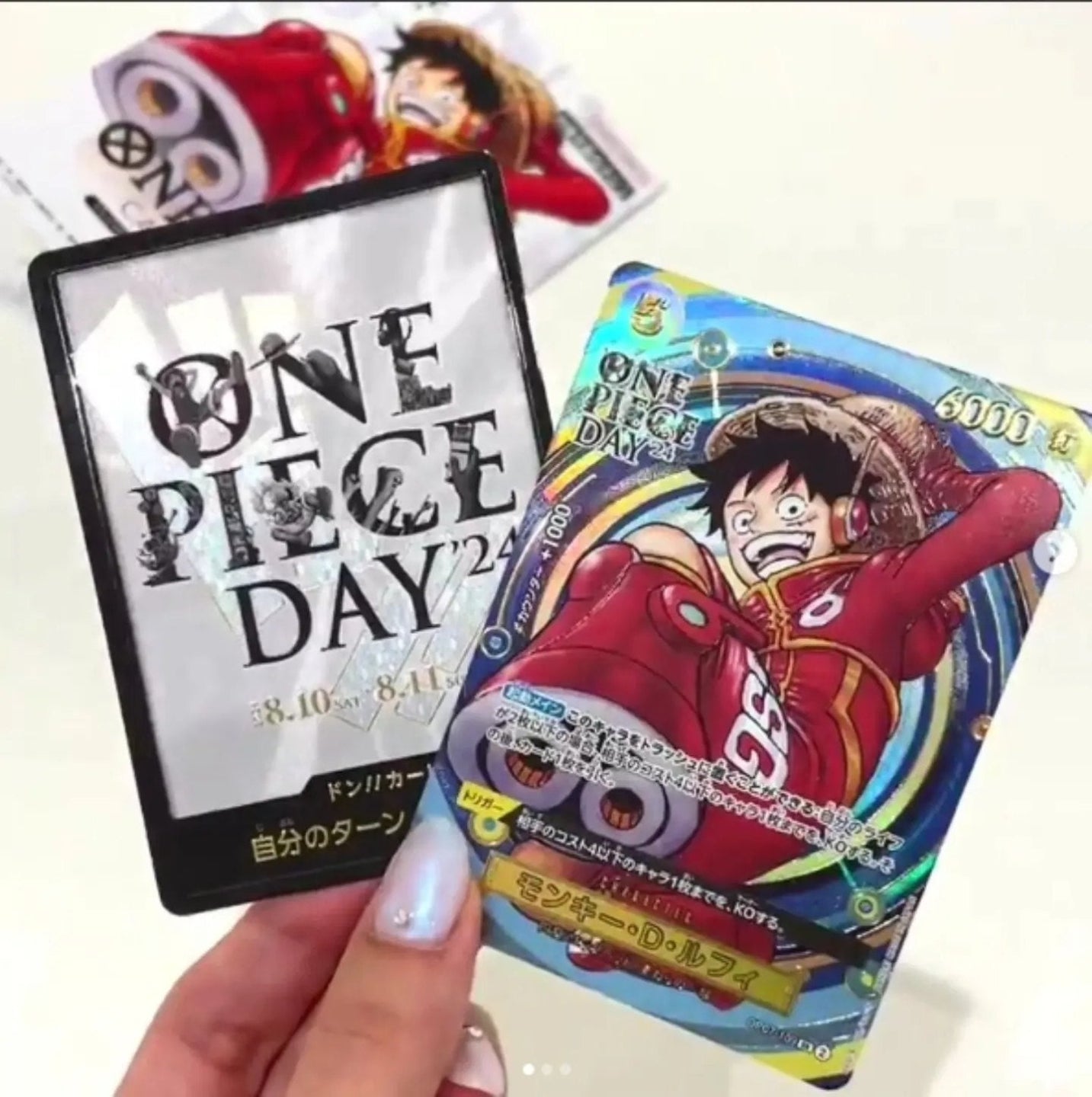 One Piece Day 24 cards held by a hand on a white background