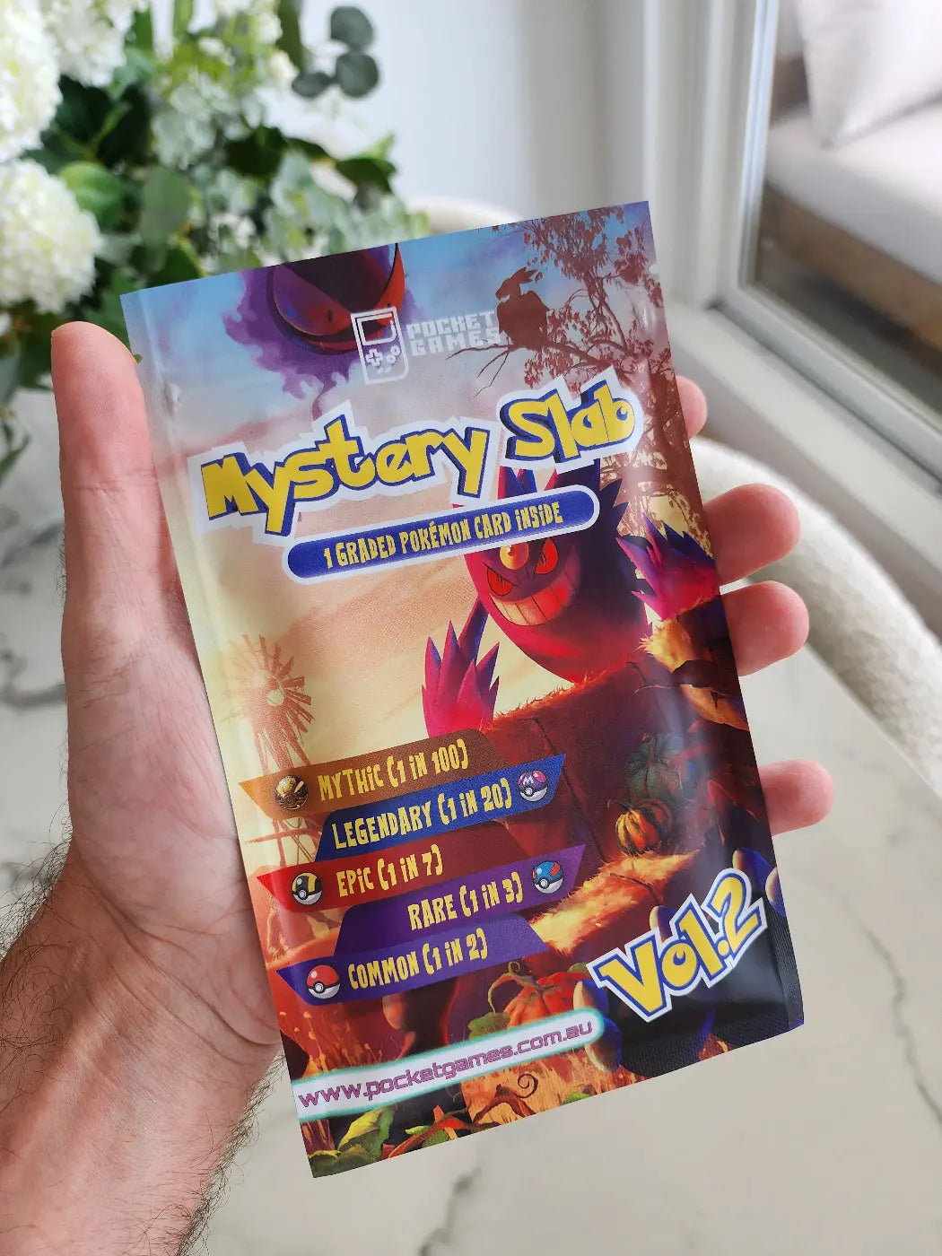 Hand holding a colorful trading card with 'Mystery Slab' text against a blurred indoor background.