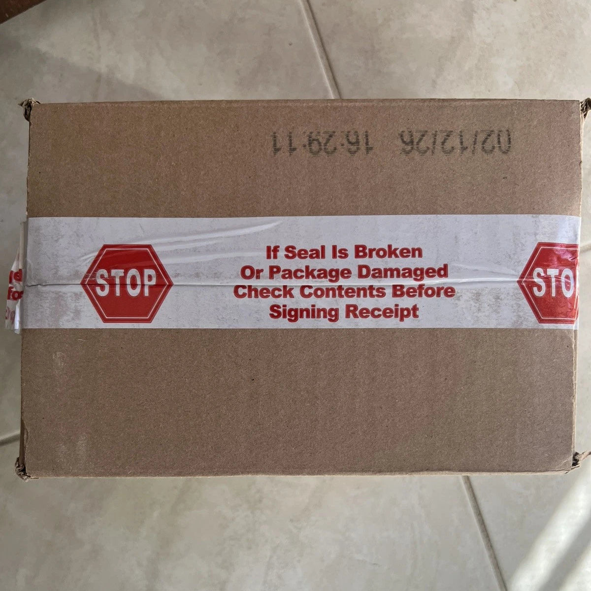 Cardboard box with a warning label on a tiled floor